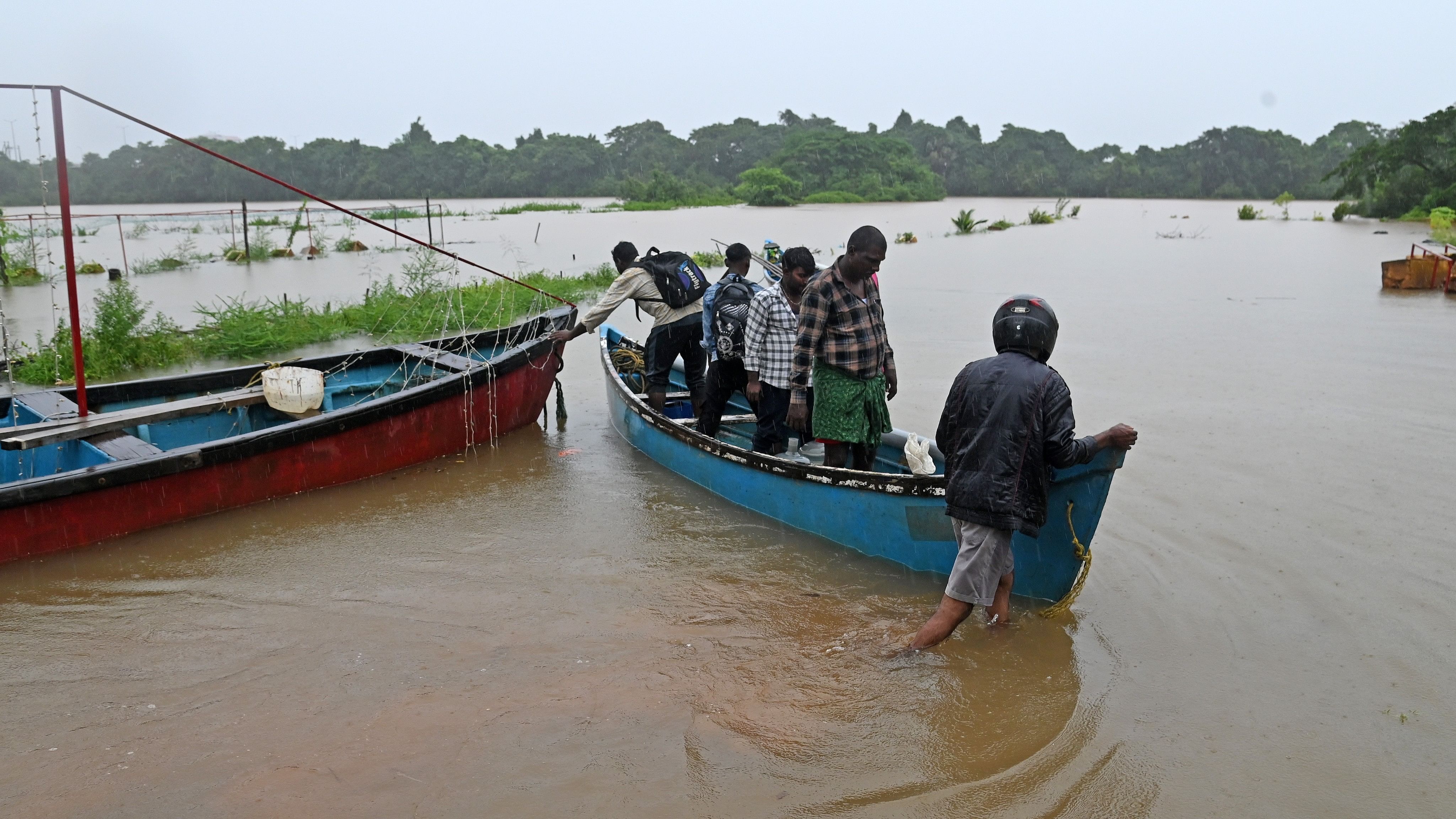 <div class="paragraphs"><p>People use boats to reach the anchored fishing boats after water entered the road at Adamkudru in Mangaluru on Tuesday.</p></div>